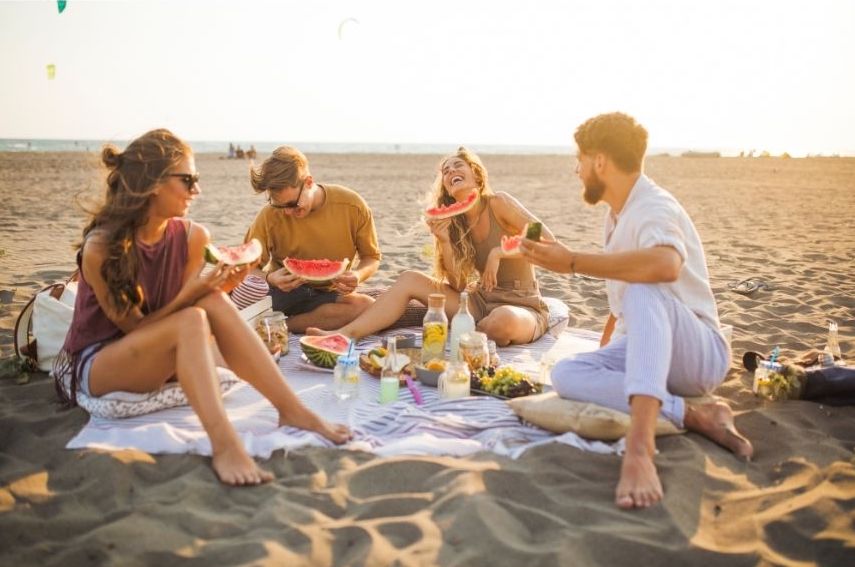A group of friends enjoys a beach picnic together.