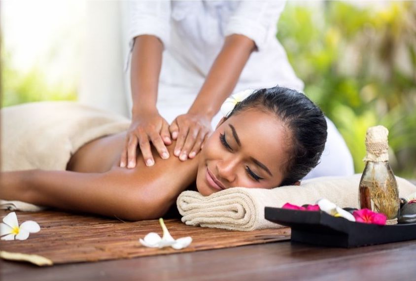 Guest enjoying a signature massage with tropical oils and frangipani flowers at a luxury wellness retreat for couples.